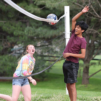 学生 playing sand volleyball at party in the park