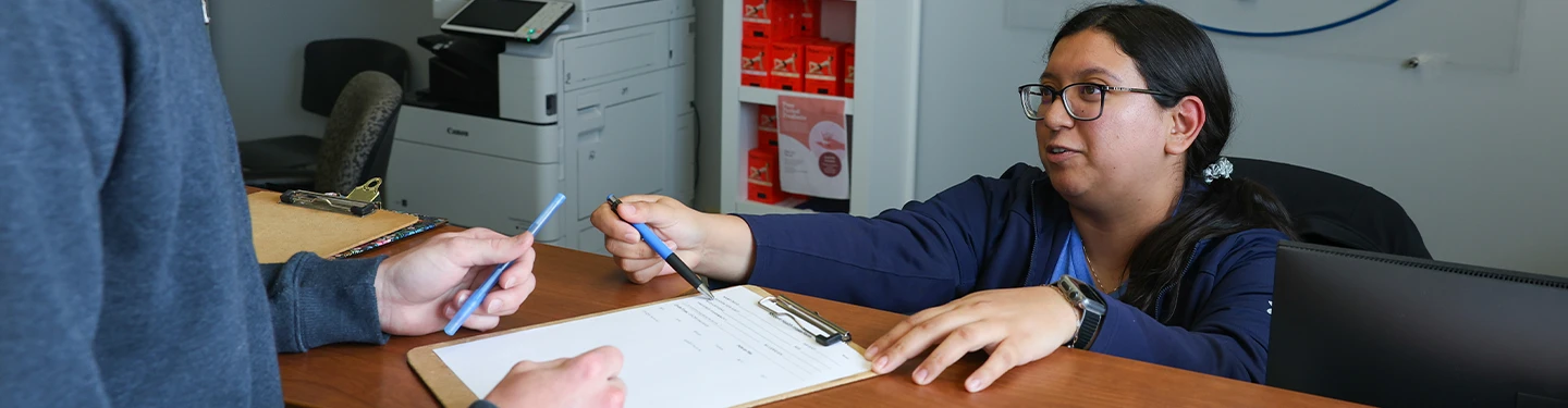 a worker helps a student with paperwork