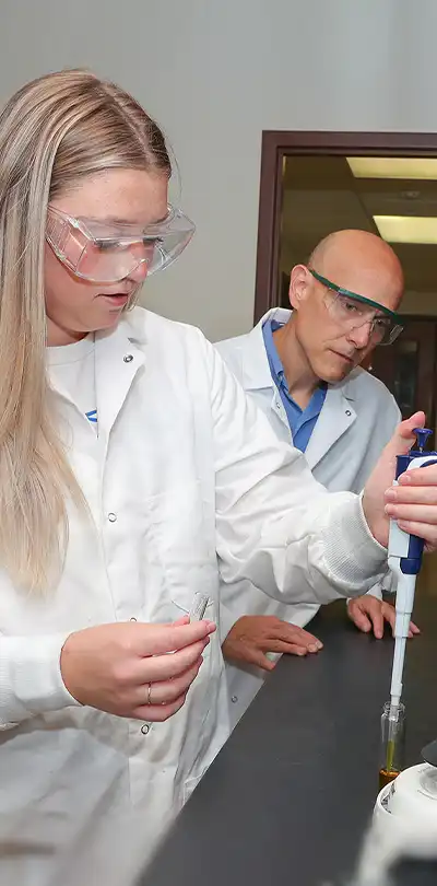 image of a student working on a lab experiment with a facult member