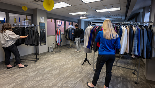 students look through racks of clothes at the career closet