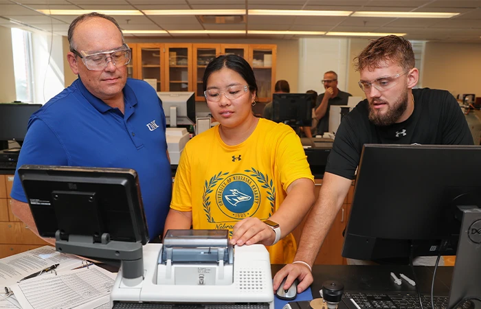 an instructor works with two students in a lab