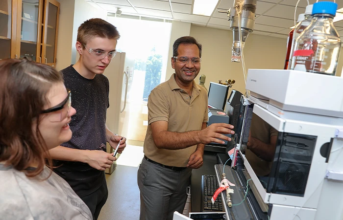 an instructor demonstrates lab equipment to two students