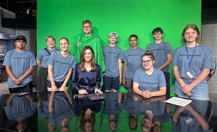 students pose for a photo on a news set