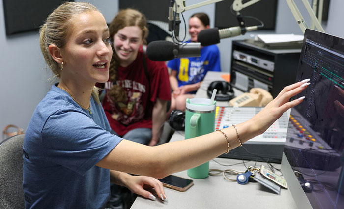 students use equipment at a radio station