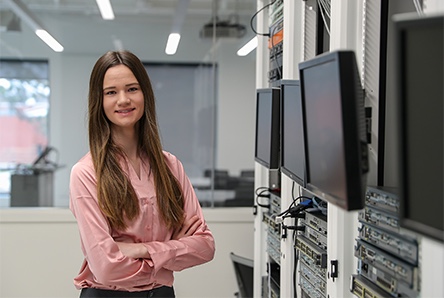 a student stands in front of a server rack