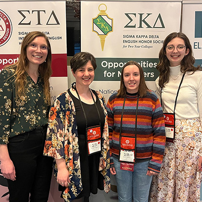 a group of students poses for a photo in front of banners at a conference