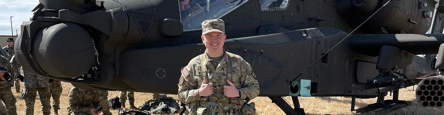 ROTC student poses in front of a helicopter