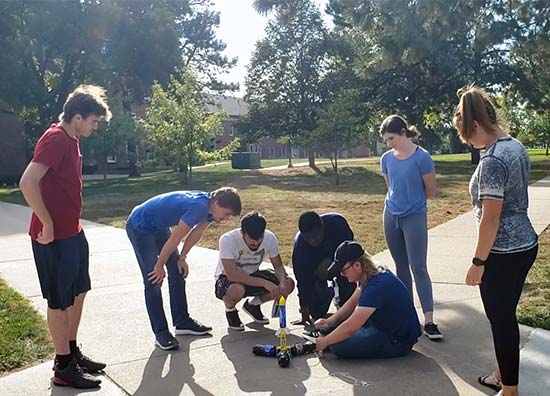 students gather around an instructor for an outdoor experiment