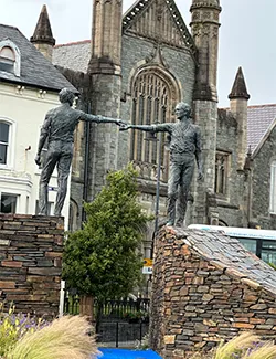 a pair of statues with their arms outstretched, touching each other