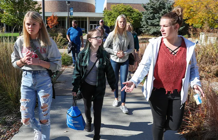 a tour guide and group talk while walking across campus