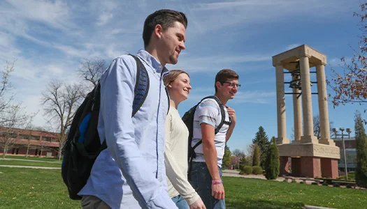 students walk across campus on a sunny day