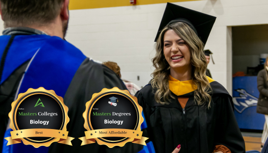 Woman in cap and gown talking with professor.