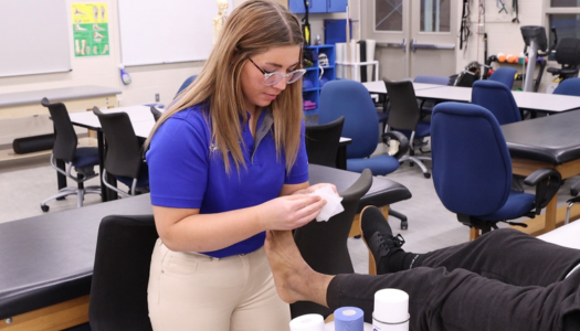 Woman wrapping an athletes ankle.