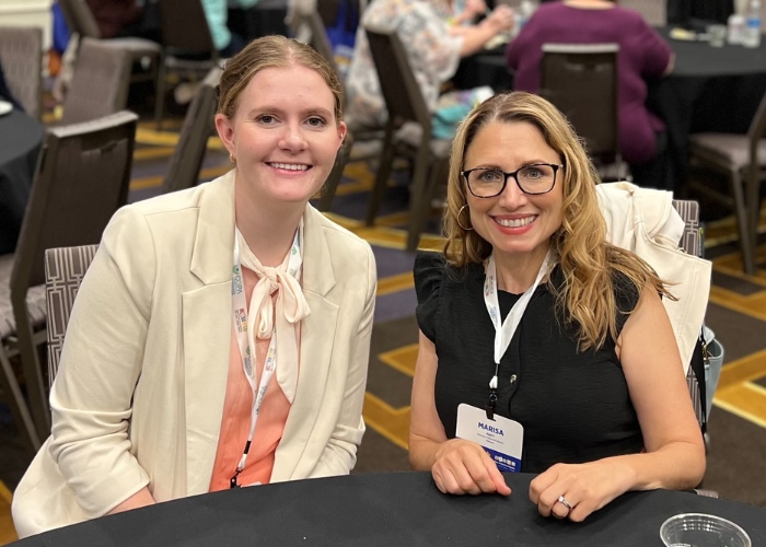 Two women sitting at a table smiling at the camera.