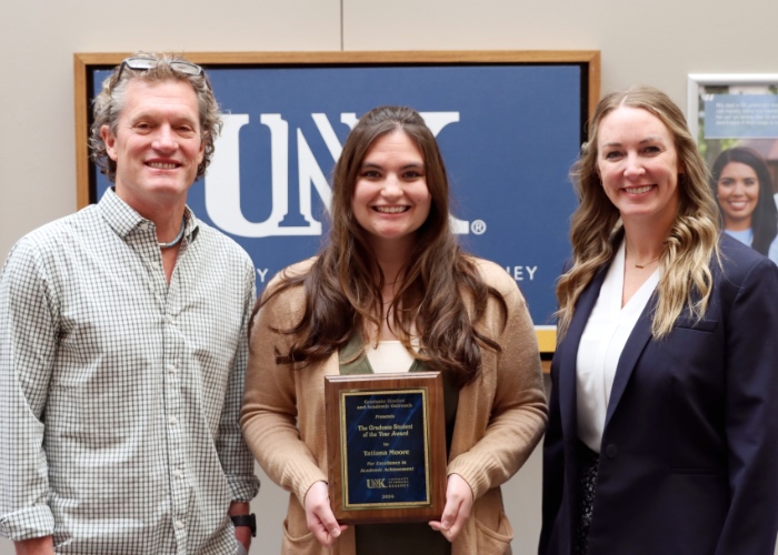 Man and woman presenting an award to a woman.