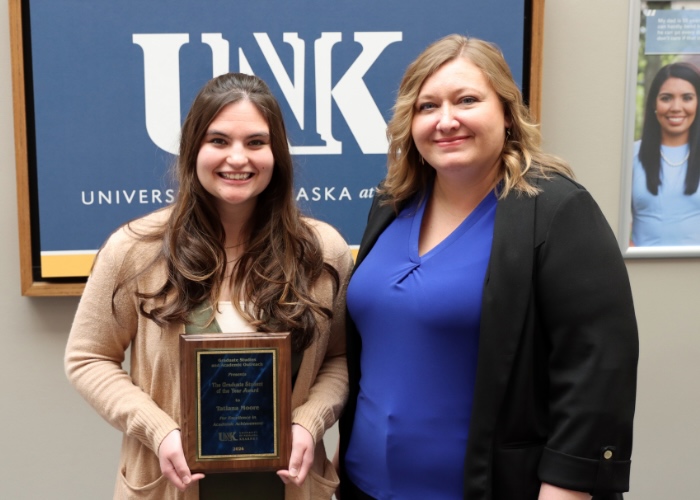 Two women, one is holding an award.