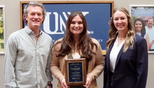 Man and woman presenting an award to a woman.