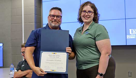 Dr. Christopher Strickland receiving the certificate for Outstanding Innovation in 在线 Teaching award from the previous year's winner, Dr. Amanda Sladek.