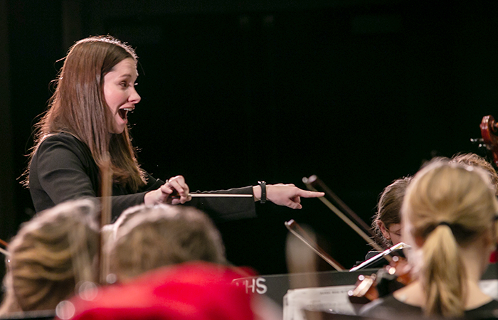 A woman conductor leads an orchestral performance.