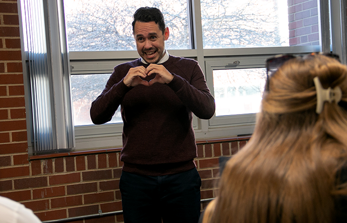 Spanish teacher forming a heart with his hands during a Spanish lesson.
