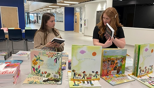 Two female teachers skimming through free books at 太阳城娱乐官网's event.