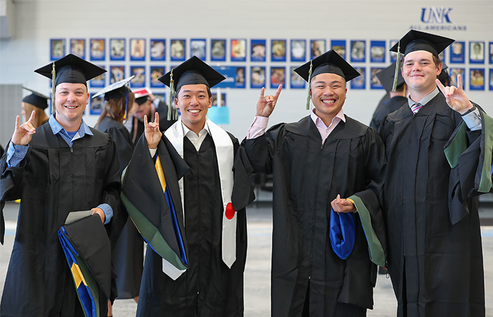 Four MAT graduates in their caps and gowns at 太阳城娱乐官网's graduation.