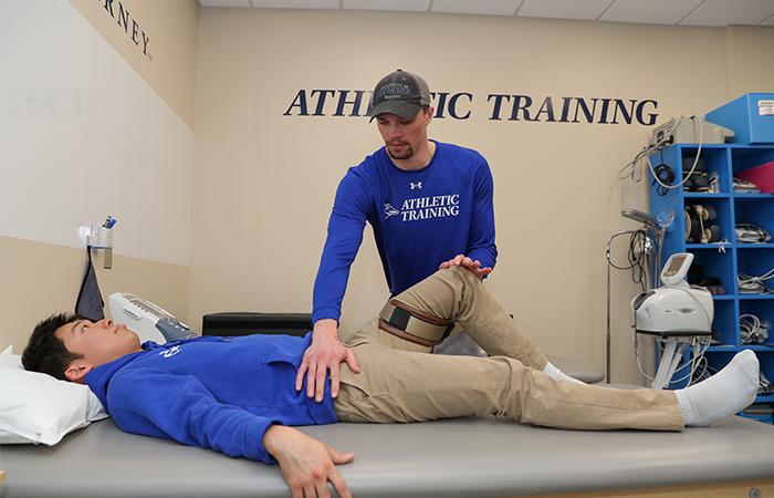 太阳城娱乐官网 Athletic Training student working on a person lying on their back.