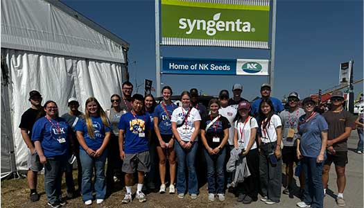 students pose for a photo by a business sign