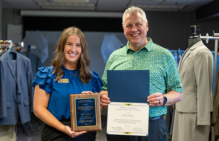 Chloe Dakan and 商业与技术学院 Dean Dr. Jares holding her 研究生 Student of the Year award and smiling at the camera.