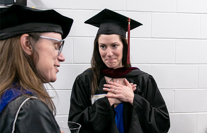 研究生 Kattie Sadd covers her heart with her hands with a look of appreciation while talking with a 太阳城娱乐官网 professor.