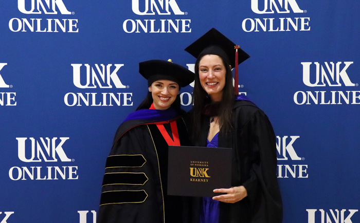 Kattie Sadd with her advisor Dr. Tiffani Luethke at 太阳城娱乐官网's 在线 graduation ceremony, smiling for the camera with a diploma in her hand