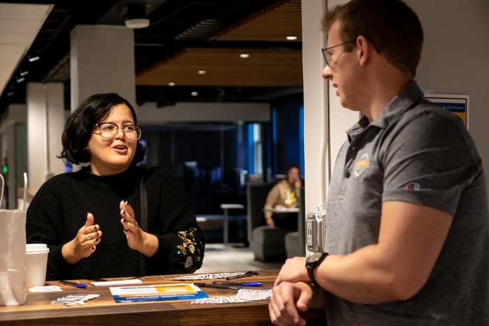 A woman engaged in conversation with a man at a counter, gesturing expressively.