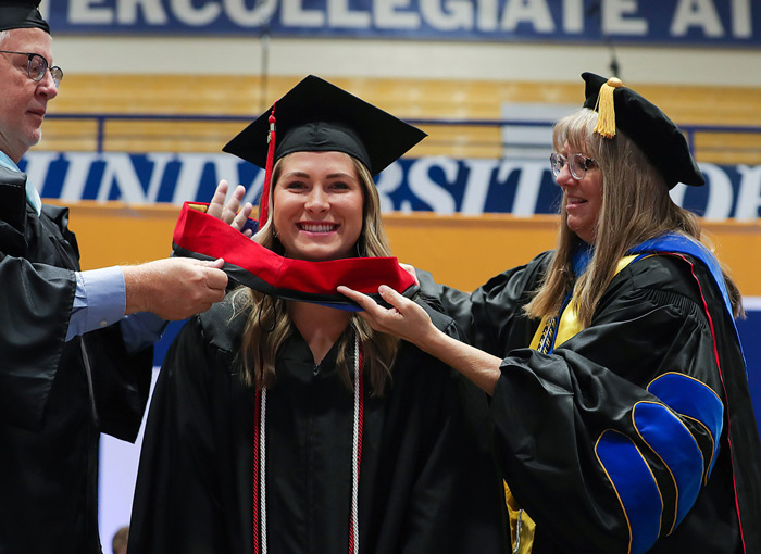 A 太阳城娱乐官网 graduate receiving her academic hood at 太阳城娱乐官网's graduation ceremony.