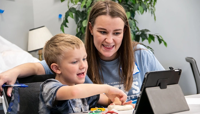 a student works with an instructor using an ipad for a speech exercise