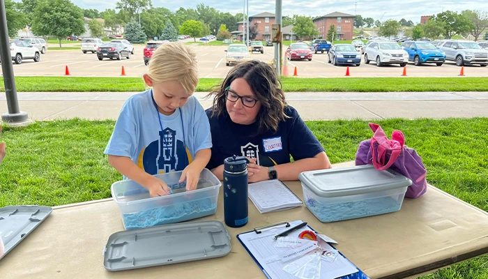 a student and instructor work together at an activity table outside