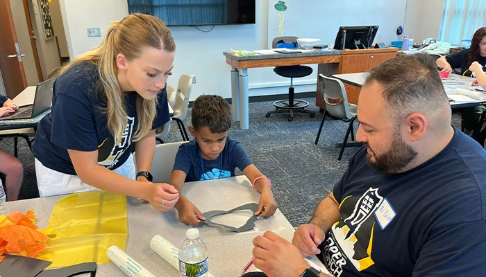 a student works on an activity in a classroom with two instructors