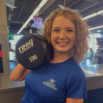 a staff member similes and holds up a weight