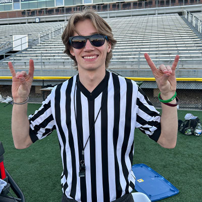 a student worker wearing referee gear smiles and throws the lopes