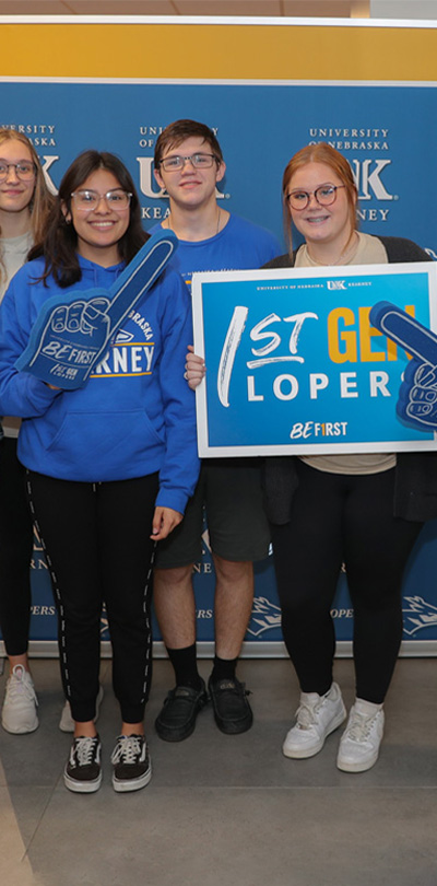 students pose for a photo holding up a first generation sign