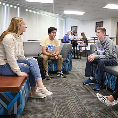 学生 sitting on couches talking to each other