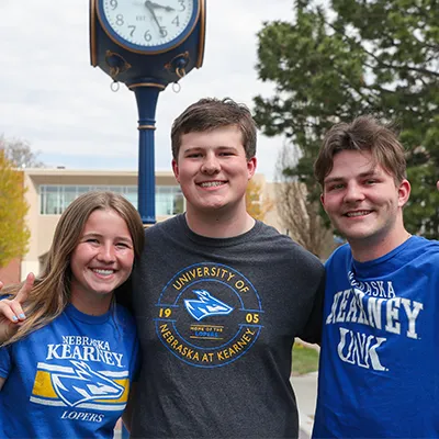students pose for a photo in front of a decorative clock